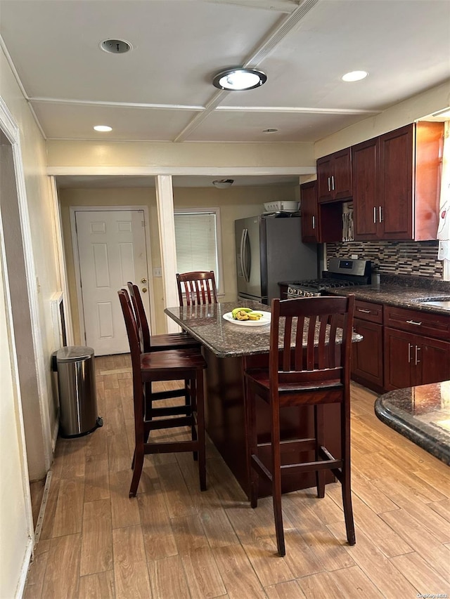 kitchen with a center island, a breakfast bar area, light wood-type flooring, tasteful backsplash, and stainless steel appliances