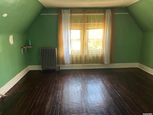 additional living space with radiator, lofted ceiling, and dark hardwood / wood-style floors