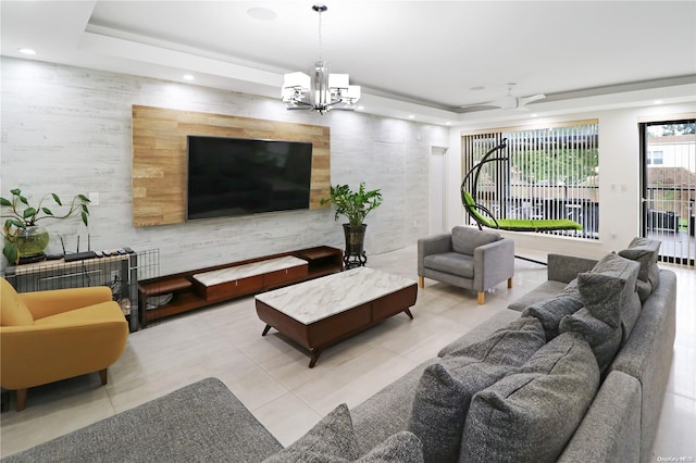 living room with ceiling fan with notable chandelier, a raised ceiling, and light tile patterned floors