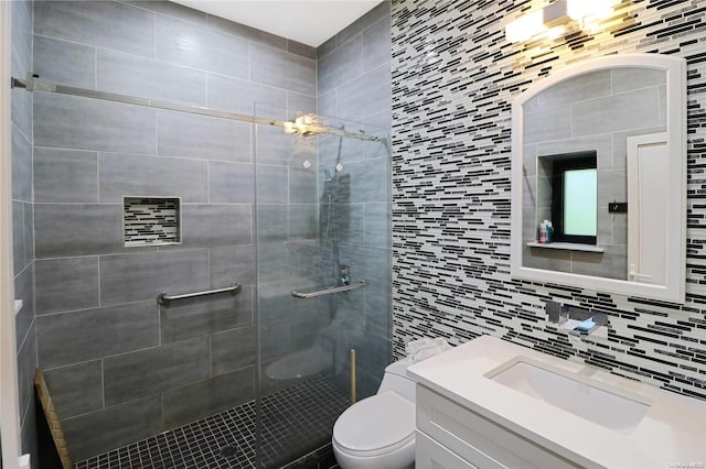 bathroom with vanity, decorative backsplash, toilet, tiled shower, and tile walls