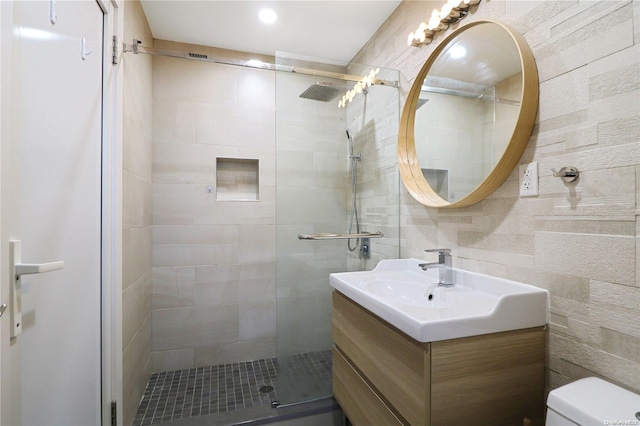 bathroom with vanity, tasteful backsplash, toilet, and a shower with shower door