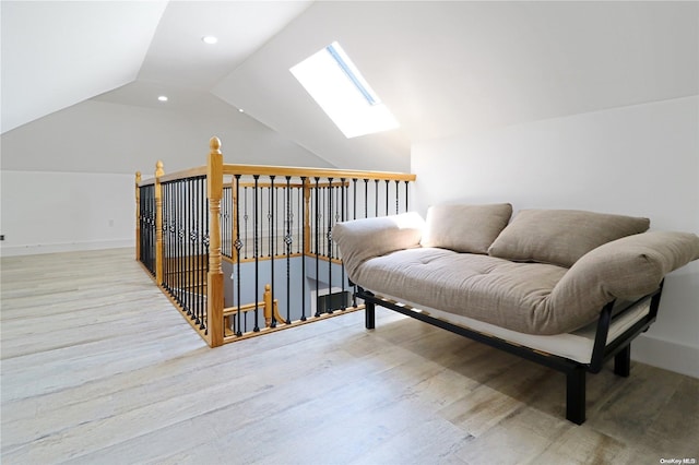 sitting room with lofted ceiling with skylight and light hardwood / wood-style flooring