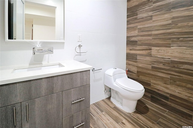 bathroom with hardwood / wood-style floors, vanity, toilet, and tile walls