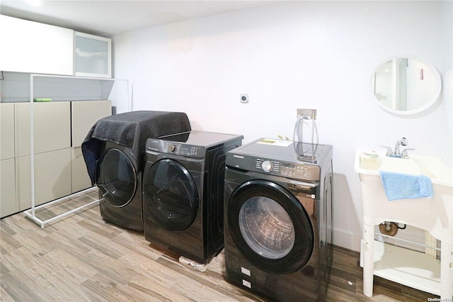 laundry room featuring separate washer and dryer and light hardwood / wood-style flooring