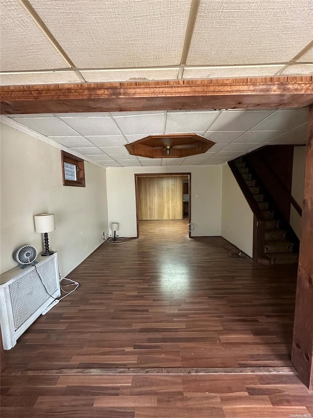 basement featuring a paneled ceiling and dark wood-type flooring