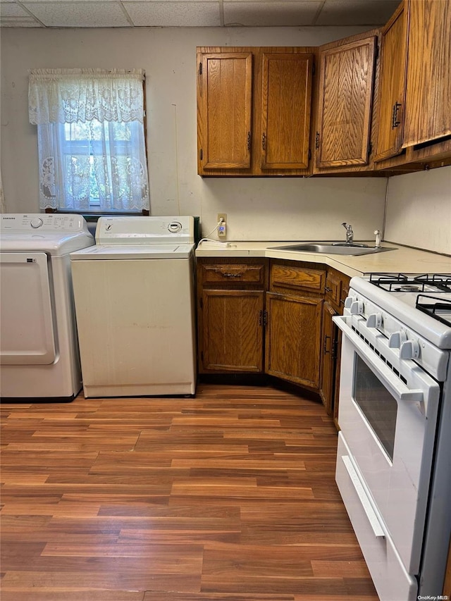 washroom with washing machine and clothes dryer, sink, and dark hardwood / wood-style floors