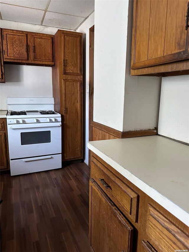 kitchen featuring a drop ceiling, white gas range oven, and dark wood-type flooring