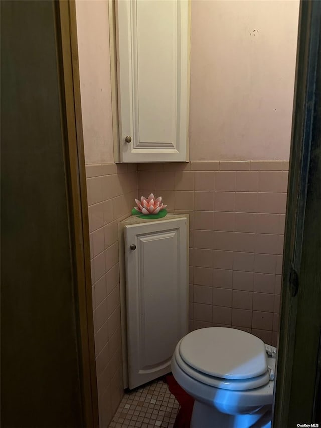 bathroom with toilet and tile walls