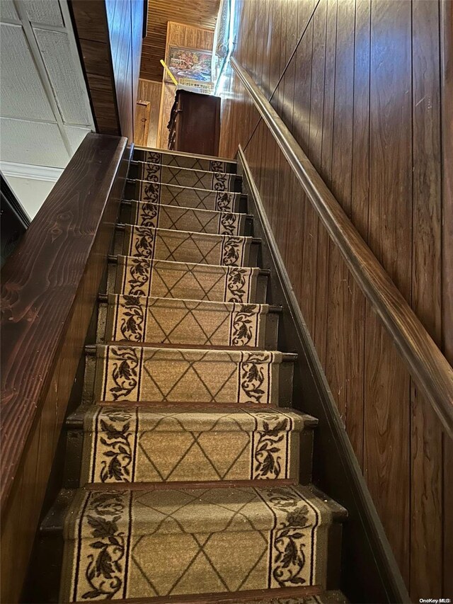 staircase featuring wooden walls