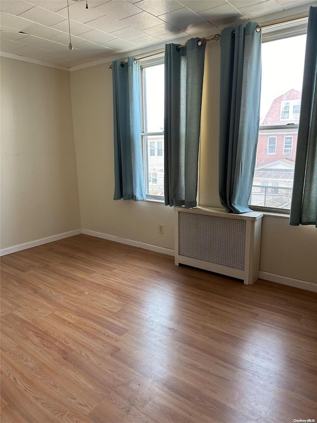 unfurnished room with radiator, crown molding, and light wood-type flooring