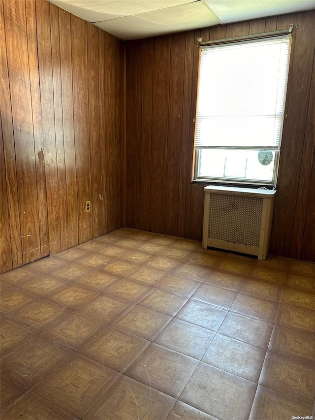 empty room with wood walls and radiator heating unit