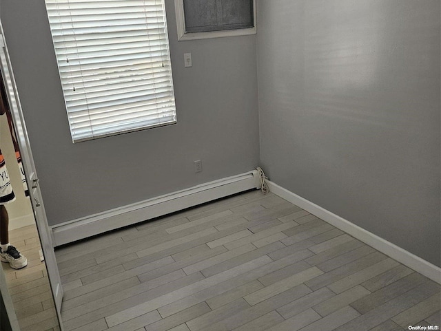 spare room featuring a baseboard heating unit and light hardwood / wood-style flooring