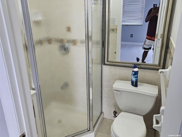 bathroom with tile patterned flooring, toilet, and a shower with door