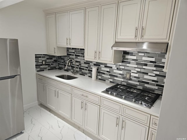 kitchen featuring stainless steel refrigerator, sink, gas stovetop, tasteful backsplash, and light stone counters