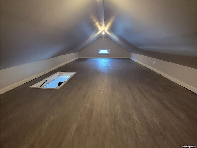 additional living space featuring dark wood-type flooring and lofted ceiling