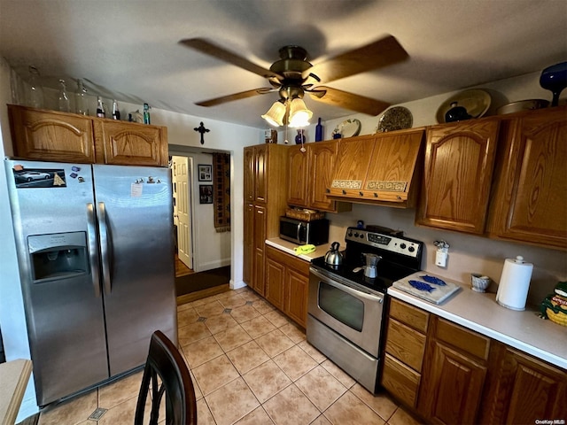 kitchen featuring ceiling fan, light tile patterned floors, stainless steel appliances, and range hood