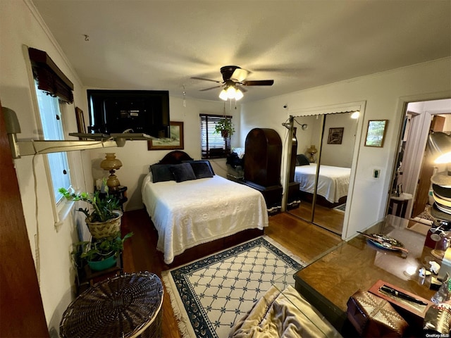 bedroom with ceiling fan, wood-type flooring, ornamental molding, and a closet