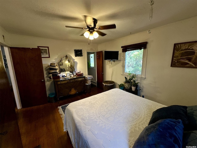 bedroom with ceiling fan, baseboard heating, and dark wood-type flooring