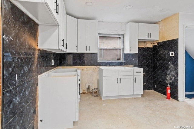 kitchen with white cabinets and tile walls