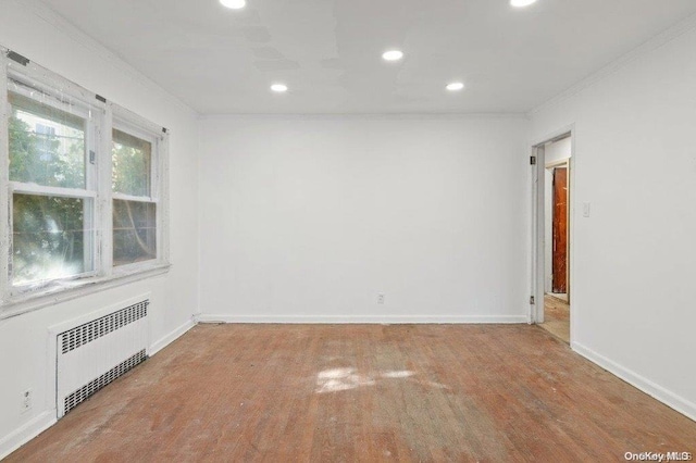 empty room featuring radiator, hardwood / wood-style floors, and ornamental molding