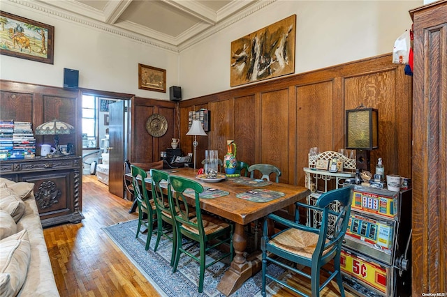 dining space featuring a high ceiling, coffered ceiling, hardwood / wood-style flooring, ornamental molding, and beamed ceiling