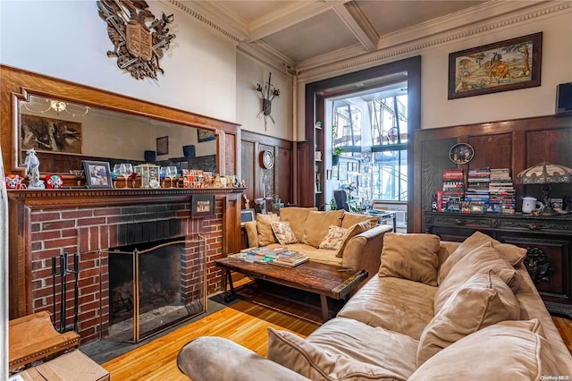 living room featuring hardwood / wood-style flooring, crown molding, coffered ceiling, and a brick fireplace