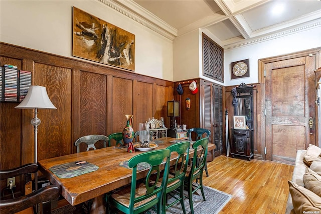 dining area featuring coffered ceiling, light wood-type flooring, ornamental molding, a towering ceiling, and beam ceiling