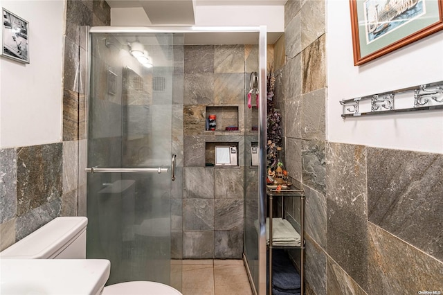 bathroom featuring tile patterned flooring, toilet, tile walls, and walk in shower