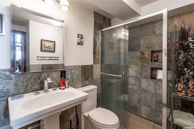 bathroom with a shower with door, toilet, tile walls, and sink