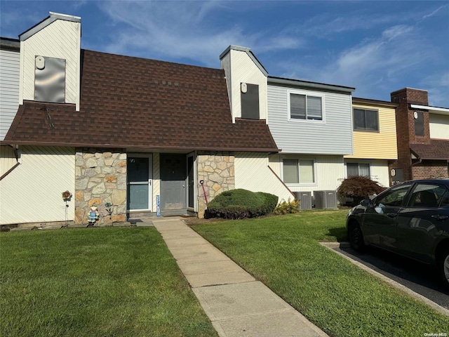 view of front of house with central air condition unit and a front lawn