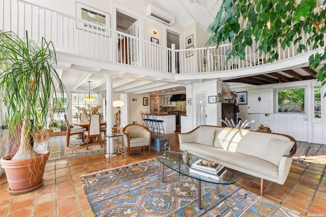 tiled living room featuring an AC wall unit, ornate columns, and beamed ceiling