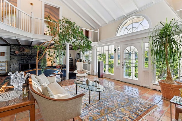 sunroom with lofted ceiling with beams and a stone fireplace