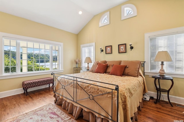 bedroom featuring hardwood / wood-style floors, vaulted ceiling, and multiple windows