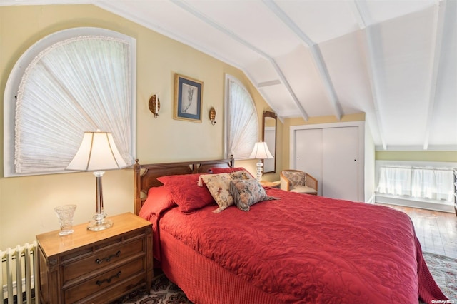 bedroom featuring hardwood / wood-style floors, vaulted ceiling with beams, a closet, and radiator