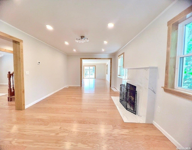 unfurnished living room featuring light hardwood / wood-style flooring, crown molding, and a premium fireplace