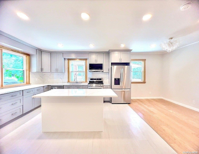 kitchen with appliances with stainless steel finishes, light hardwood / wood-style flooring, a wealth of natural light, and sink