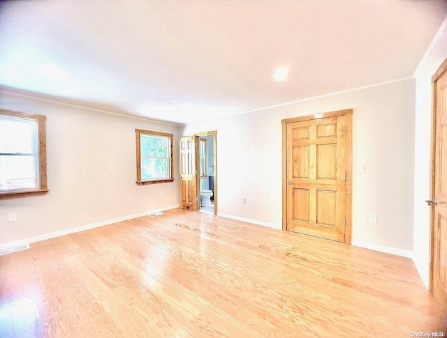 spare room with a wealth of natural light, crown molding, and light hardwood / wood-style floors