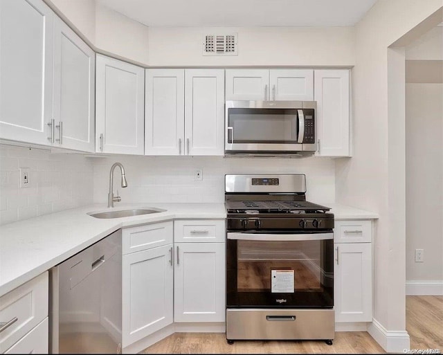 kitchen with light countertops, visible vents, appliances with stainless steel finishes, white cabinetry, and a sink