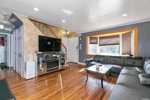 living room with crown molding, wood-type flooring, and an inviting chandelier