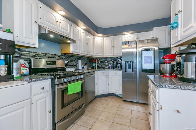 kitchen with light tile patterned floors, dark stone countertops, white cabinetry, and appliances with stainless steel finishes