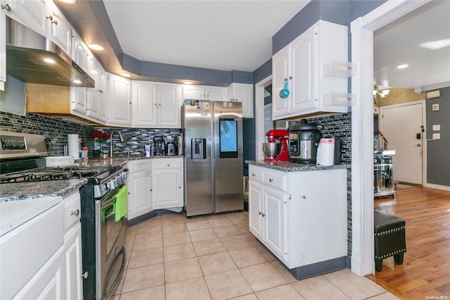 kitchen with white cabinets, appliances with stainless steel finishes, light wood-type flooring, and decorative backsplash