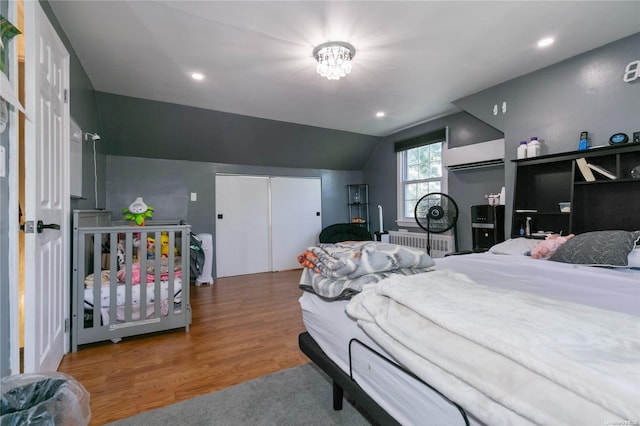 bedroom with hardwood / wood-style floors, radiator heating unit, and vaulted ceiling