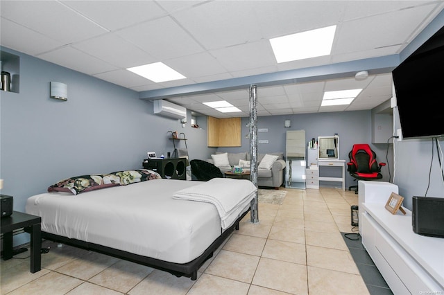 bedroom with light tile patterned floors, a paneled ceiling, and a wall unit AC