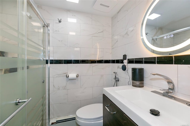 bathroom featuring toilet, decorative backsplash, a shower with door, vanity, and tile walls