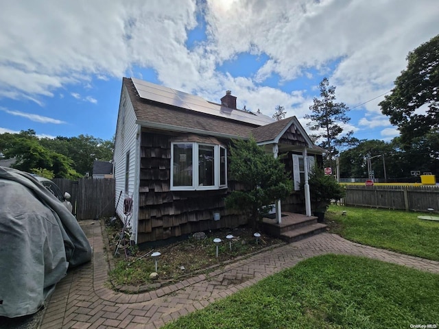 bungalow featuring solar panels and a front lawn