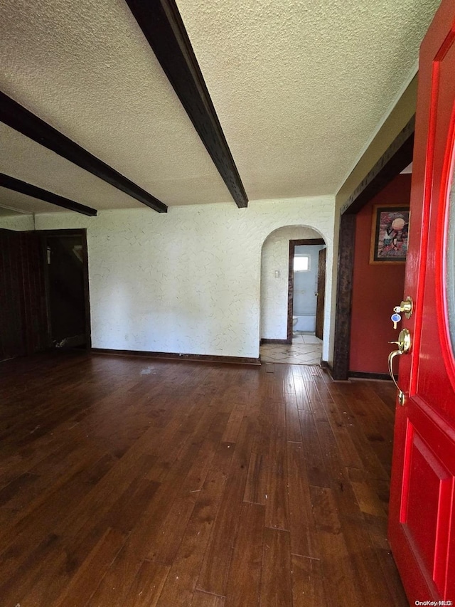 interior space with dark hardwood / wood-style floors, beam ceiling, and a textured ceiling