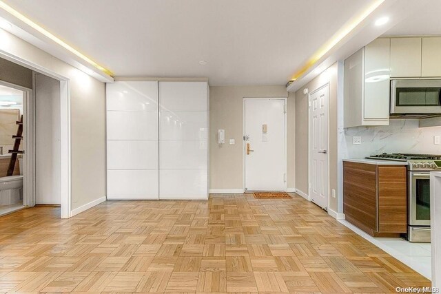 interior space with tasteful backsplash, stainless steel appliances, and light parquet flooring