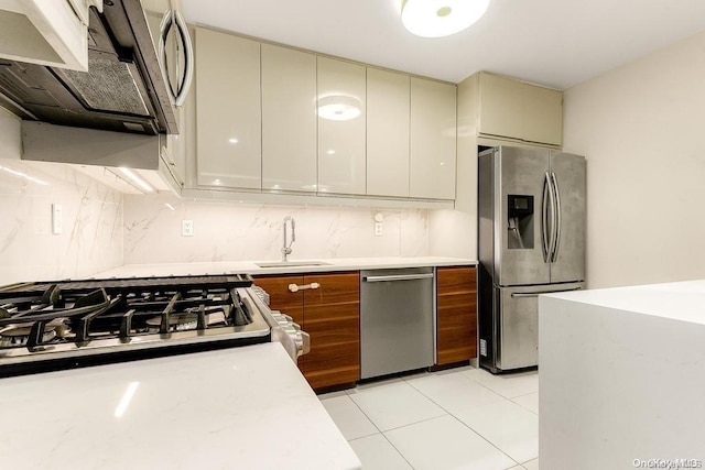 kitchen with sink, appliances with stainless steel finishes, tasteful backsplash, cream cabinetry, and light tile patterned flooring