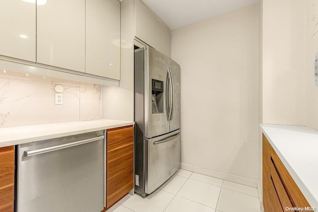 kitchen featuring appliances with stainless steel finishes, tasteful backsplash, white cabinetry, and light tile patterned flooring