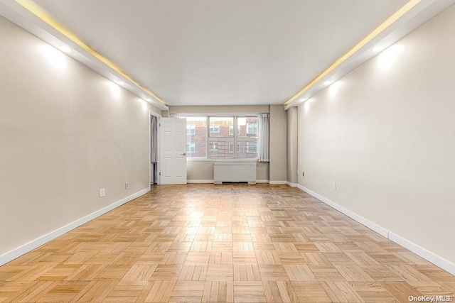 spare room featuring radiator and light parquet floors